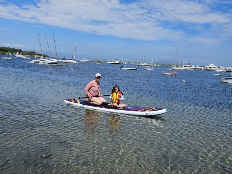 An adult and child on a paddle board in the pond on Cuttyhunk